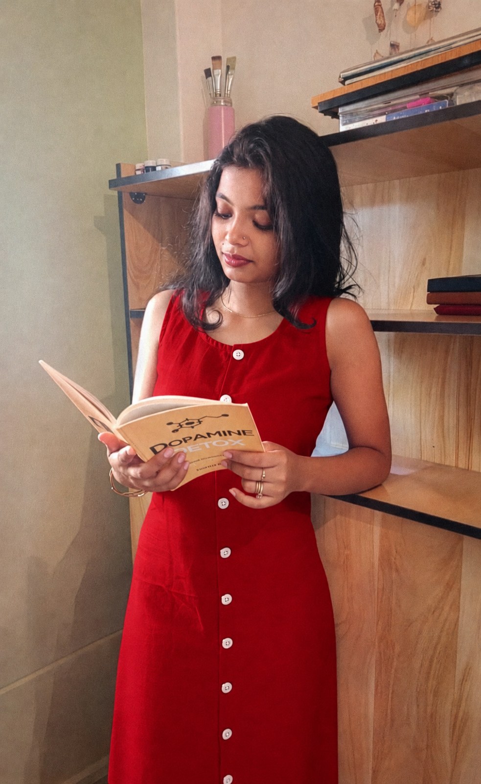 Model reading a book in the Noor sleeveless red cotton midi dress